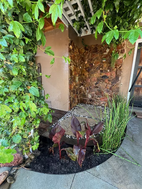 Outdoor patio with stone veneer, circular pavers, pergola, and landscaping